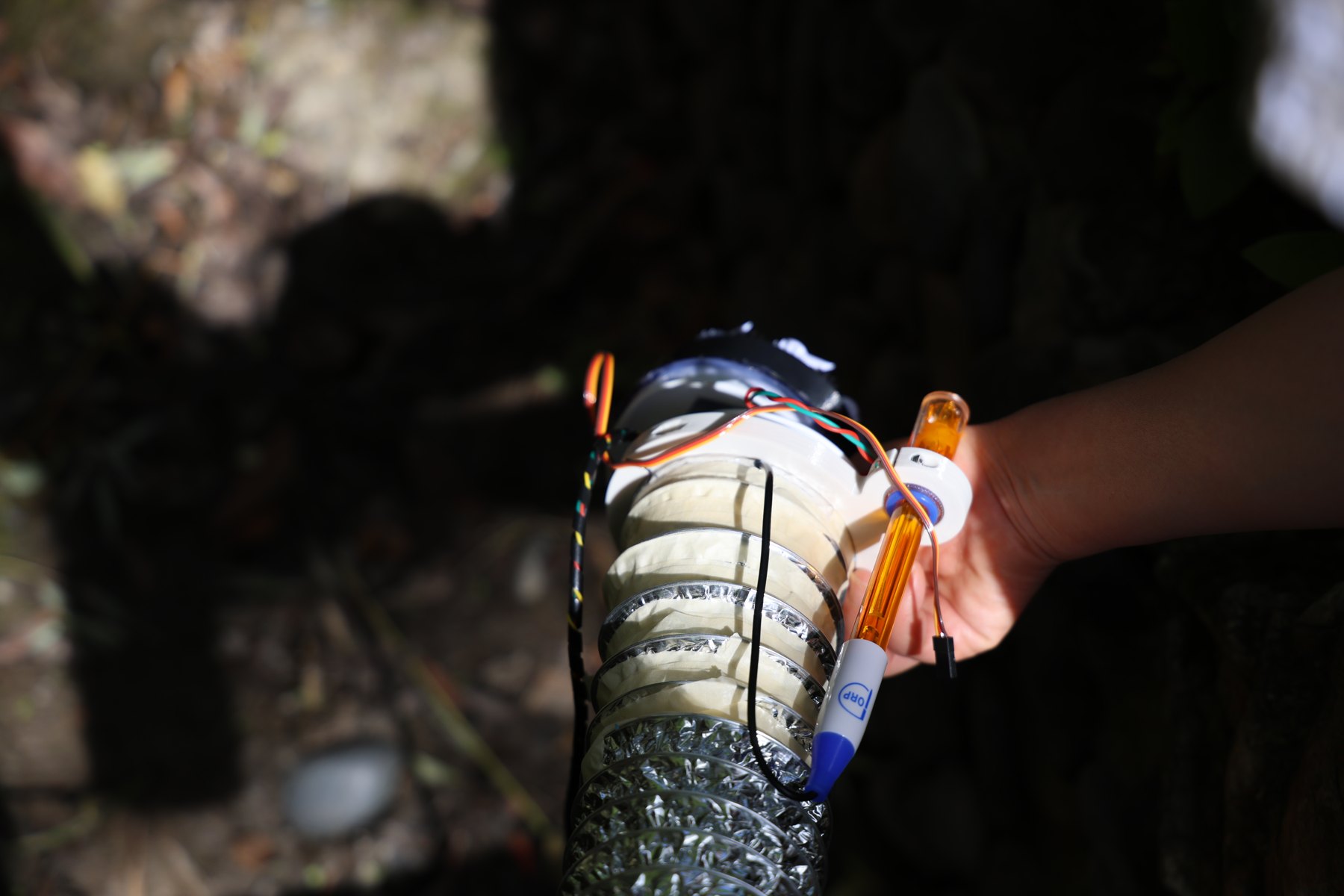 A hand holding the robot with a water-quality probe attached.